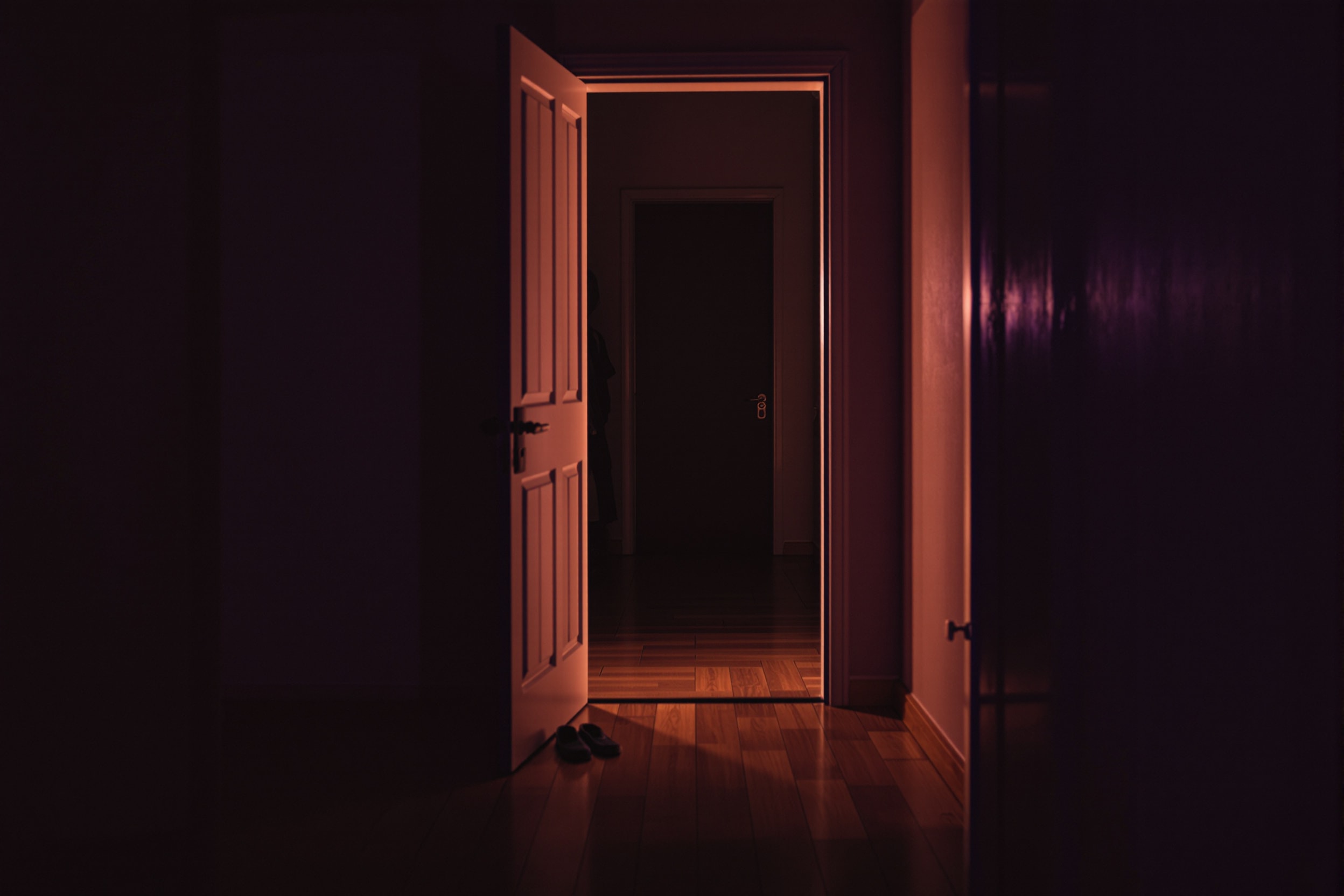 An open bedroom doorway with warm light spilling from a hallway
